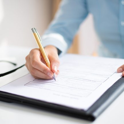 Closeup of business woman making notes in document. Entrepreneur sitting at desk and writing. Paperwork concept. Cropped view.